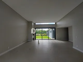Espaço interno amplo com piso claro e porta de vidro que dá para o jardim.