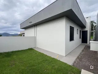 Fachada moderna de uma residência em Lajeado, Brasil, com jardim gramado e muro branco.