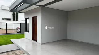 Interior de uma sala ampla com piso de cerâmica e parede branca.