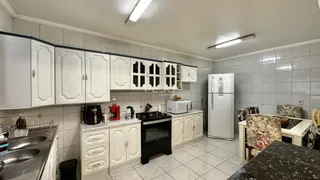 Cozinha com armários brancos e piso de cerâmica clara.