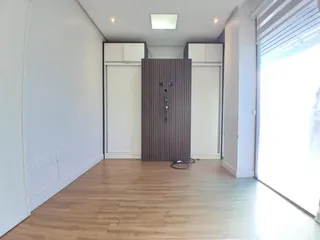 Hall de entrada com piso de madeira clara e paredes brancas.