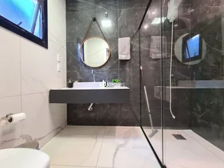 Banheiro moderno com revestimento em mármore e box de vidro.