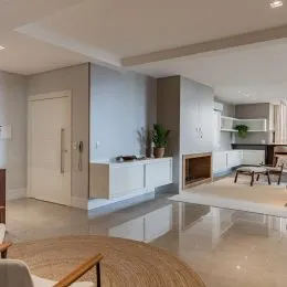 Sala de estar com piso polido e armários brancos na área interna.