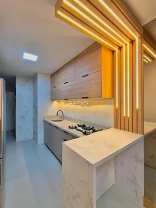 Cozinha moderna com armários de madeira e bancadas de mármore claro.