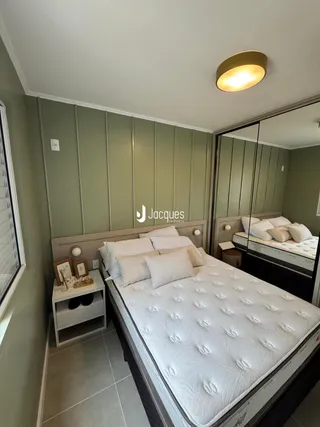 Quarto com cama de casal e paredes em tom verde claro.
