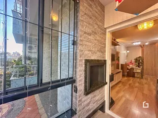 Vista interna de um apartamento com parede de pedra e porta de vidro.
