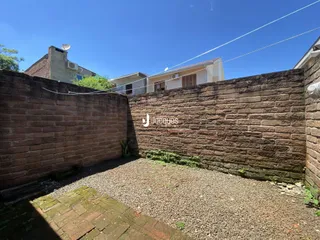 Parede de tijolos vermelhos com um terreno de cascalho no exterior de uma propriedade.