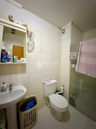 Foto de um banheiro interno com azulejos brancos e louças sanitárias.