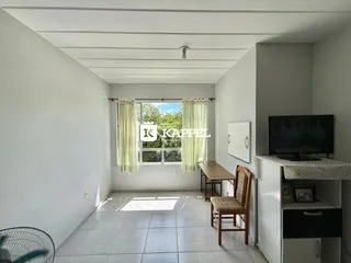 Corredor com janela e televisão em ambiente interno.