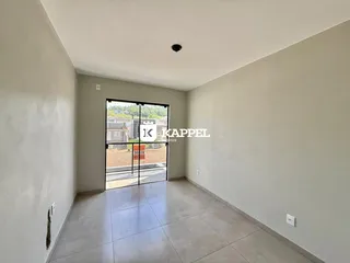 Uma foto de um corredor interno com paredes brancas e piso de cerâmica.