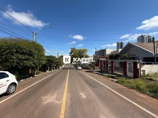 Vista de uma rua asfaltada em Lajeado com vegetação e edifícios ao fundo.