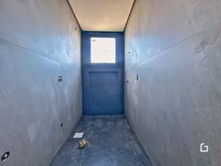 Corredor estreito com paredes azuis e piso texturizado.