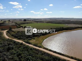 Vista panorâmica de campos verdes e um corpo d'água em uma área rural.