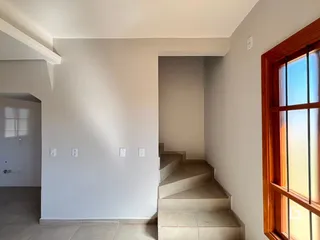 Vista de um corredor interno com escadaria e janela em uma residência.
