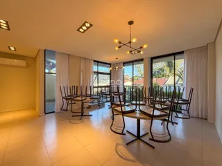 Sala de jantar ampla com mesa de madeira e grandes janelas.