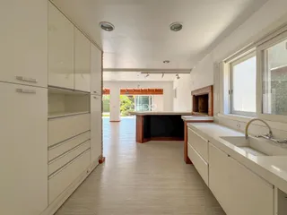 Interior de uma sala de estar com piso de madeira clara e armários brancos.