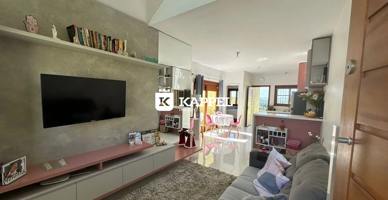 Sala de estar com sofá e televisão montada na parede em um apartamento.