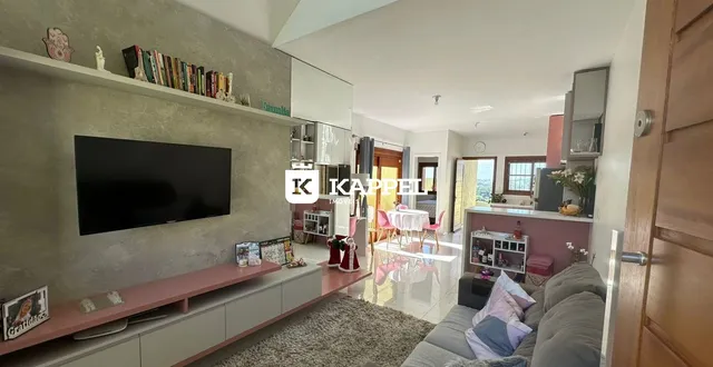 Sala de estar com sofá e televisão montada na parede em um apartamento.
