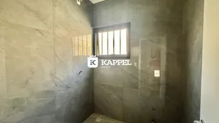 Parede revestida com azulejos cinzas e uma janela vertical.