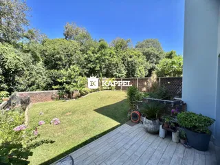 Um jardim gramado com muro de tijolos e vegetação exuberante é visível no quintal da propriedade.