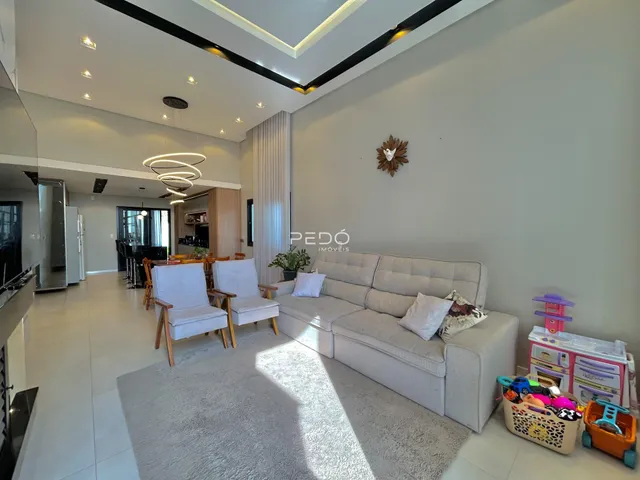Sala de estar moderna com sofá e cadeiras em um ambiente claro.