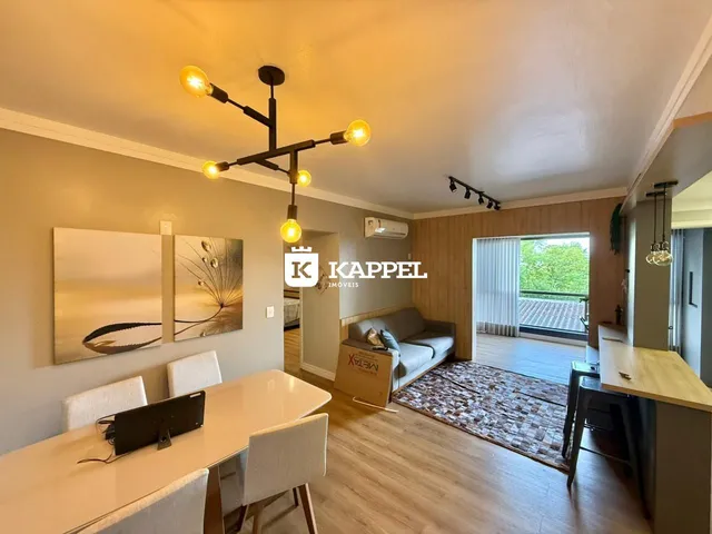 Foto interna de uma sala de estar com sofá e mesa de jantar em um imóvel.