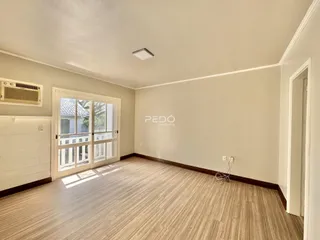 Sala de estar com piso de madeira e portas de vidro de acesso ao exterior.