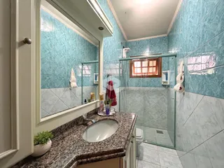 Banheiro com revestimento cerâmico azul claro e box de vidro.