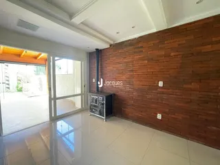 Sala de estar com parede de tijolos aparentes e piso de porcelanato claro.