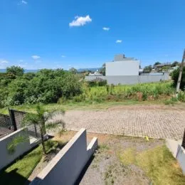 Vista externa do terreno com vegetação e céu azul.