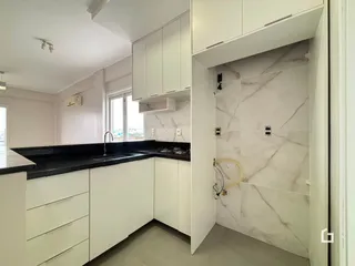 Vista da cozinha com armários brancos e bancadas escuras.