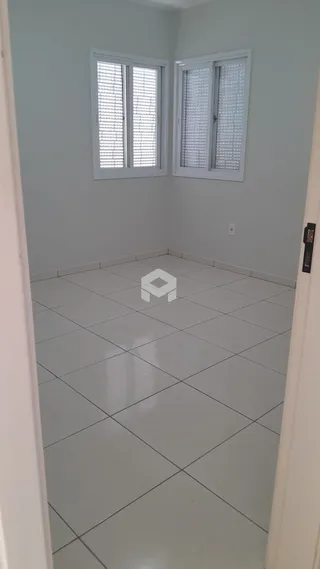 Vista de um corredor interno com piso de cerâmica e janelas.