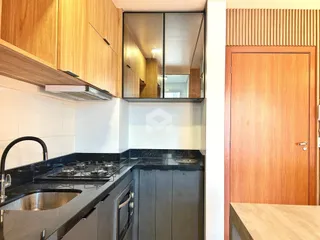 Foto da cozinha mostrando armários de madeira e bancada escura.