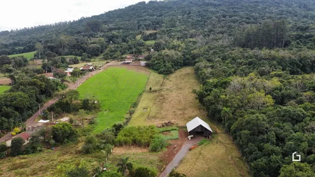 Vista aérea de uma propriedade rural com vegetação densa e áreas de pastagem.