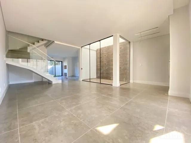 Espaço amplo e moderno com piso claro e escadaria visível.