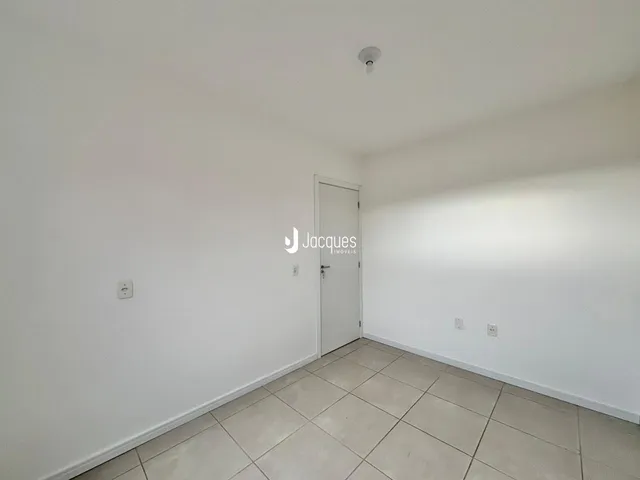 Interior de um ambiente com paredes brancas e piso de cerâmica clara.