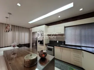 Sala de estar com área de cozinha integrada e janelas com persianas.