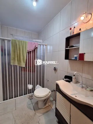 Foto interna de um banheiro com azulejos brancos e um vaso sanitário.