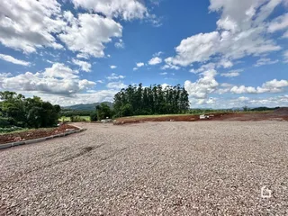 Vista de uma área de terra com vegetação e montanhas ao fundo sob um céu azul.