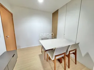 Ambiente interno de uma sala com mesa de jantar e piso de madeira clara.