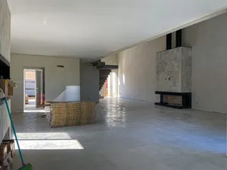Hall de uma casa em construção com piso de concreto e lareira.