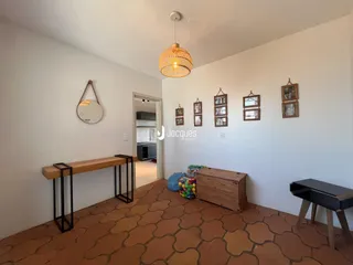 Interior de uma sala de estar com piso de terracota e paredes brancas.