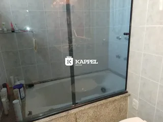 Foto de um banheiro com banheira e box de vidro.