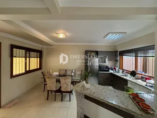 Sala de estar com janelas de madeira e área de cozinha.