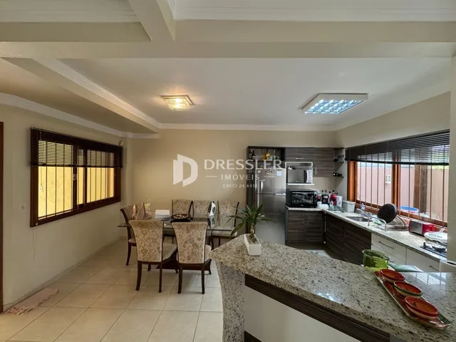 Sala de estar com janelas de madeira e área de cozinha.