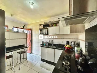 Esta é uma foto de uma cozinha moderna com armários brancos e bancadas escuras.
