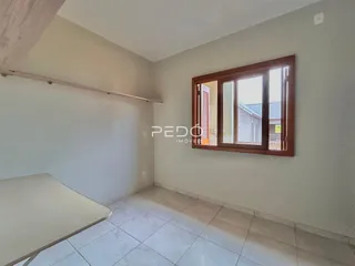 Interior de uma sala com piso de cerâmica e janela de madeira.