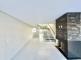 Hall de entrada longo com escadaria moderna e parede de pedra escura.