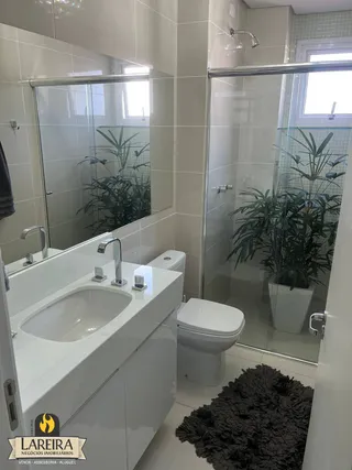 Interior de um banheiro com azulejos brancos e box de vidro.