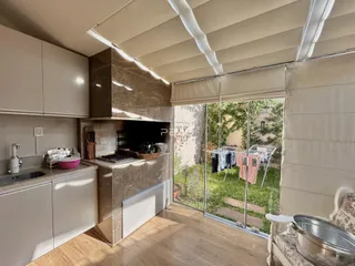 Vista da cozinha com porta de vidro que se abre para um jardim ao ar livre.